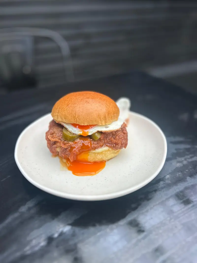 Brioche bun with pulled meat, pickles and a runny fried egg