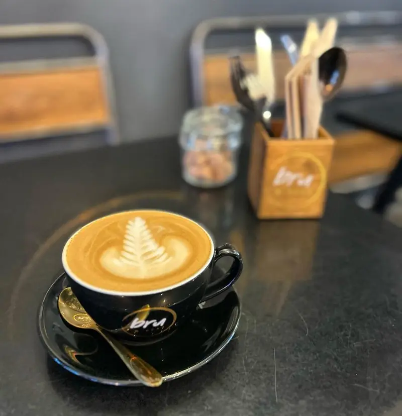 Coffee with fern latte art in a black Bru & Bear cup