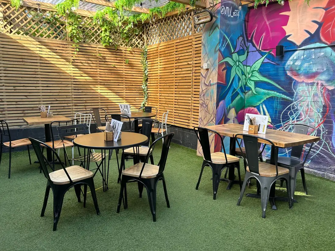 Bru & Bear courtyard garden with tables, a painted jellyfish mural and a wall heater