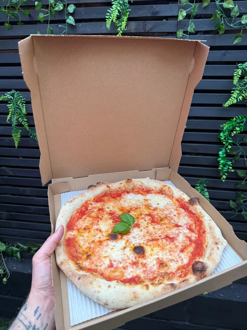 Margherita pizza with fresh basil in a takeaway box